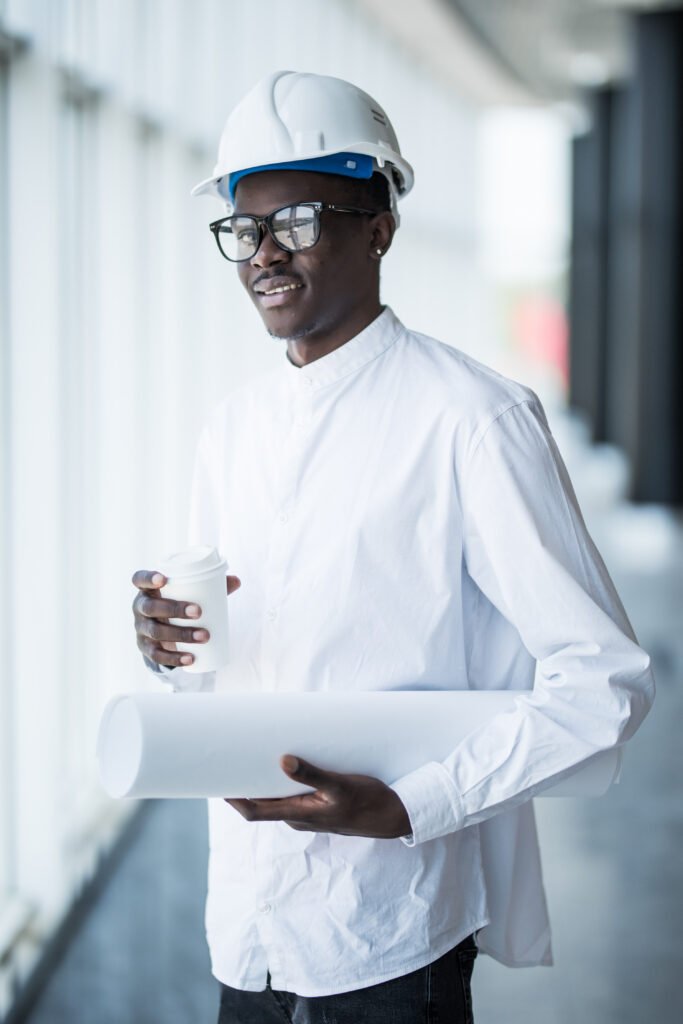 Young Afro-American engineer with blue prints in front of panora